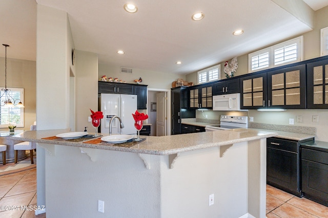 kitchen featuring a kitchen breakfast bar, light tile patterned floors, and white appliances