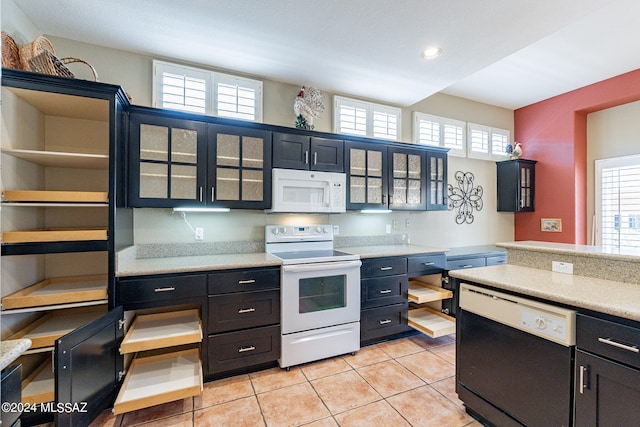 kitchen featuring a wealth of natural light, light tile patterned floors, and white appliances