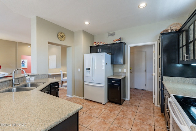 kitchen with electric range, light stone counters, light tile patterned floors, sink, and white refrigerator with ice dispenser