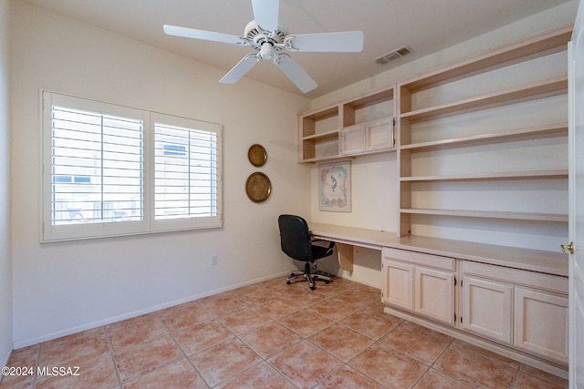 unfurnished office with built in desk, light tile patterned floors, and ceiling fan