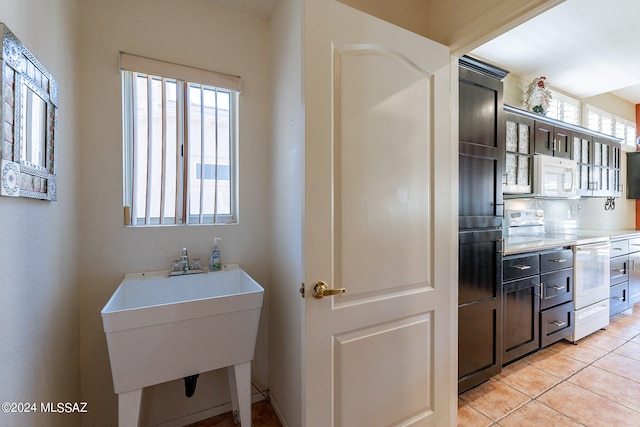 kitchen featuring white appliances, light tile patterned floors, a wealth of natural light, and sink