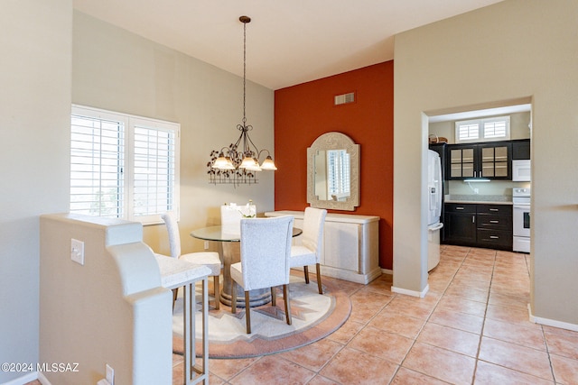 dining space featuring a notable chandelier, a towering ceiling, and light tile patterned flooring