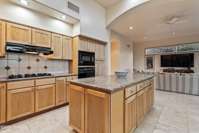 kitchen with a kitchen island, black appliances, decorative backsplash, ceiling fan, and light stone counters