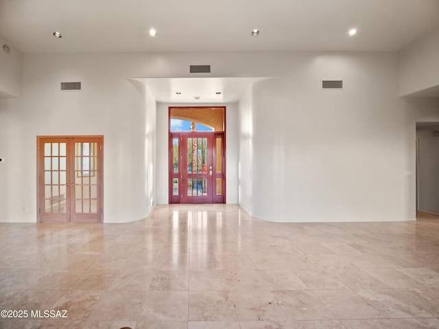 unfurnished room featuring a towering ceiling and french doors