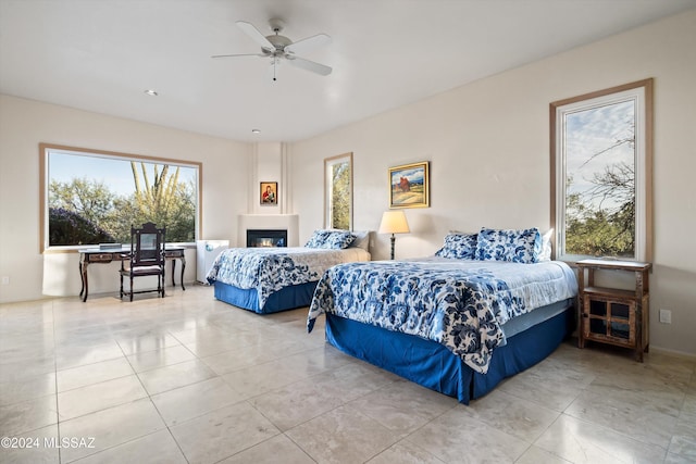 bedroom featuring ceiling fan, multiple windows, and light tile patterned floors