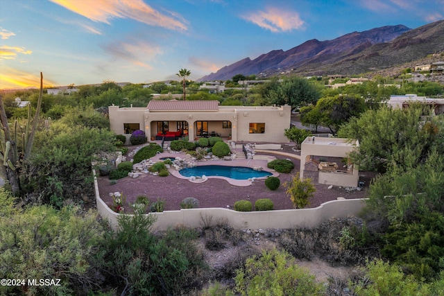 pool at dusk featuring a mountain view and a patio area