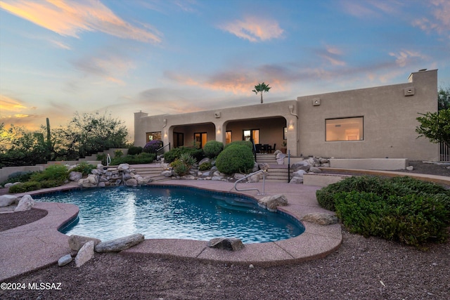 pool at dusk featuring a patio