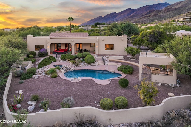 pool at dusk with a mountain view and a patio area