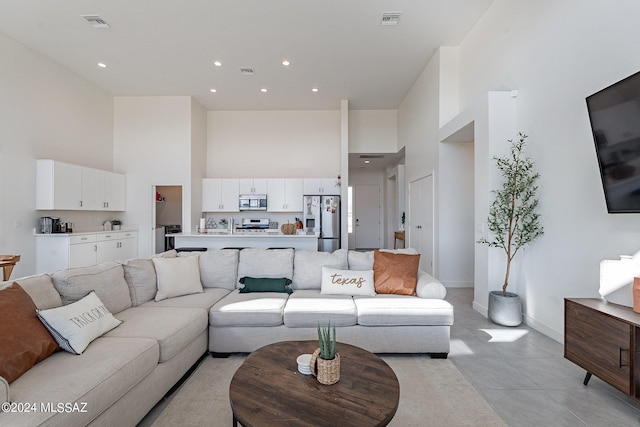 living room featuring a towering ceiling, visible vents, and recessed lighting