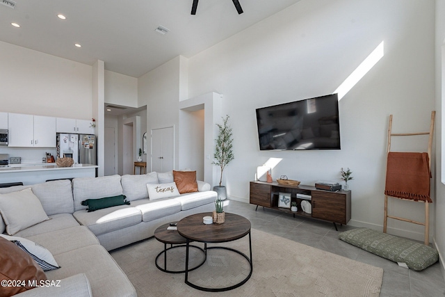 living room featuring visible vents, a towering ceiling, baseboards, and light tile patterned floors