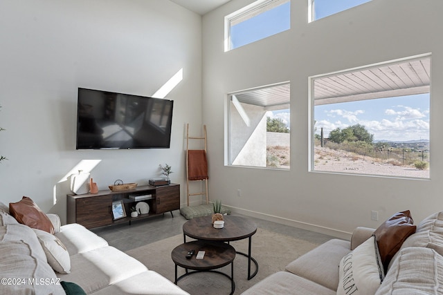 living area featuring a high ceiling and baseboards