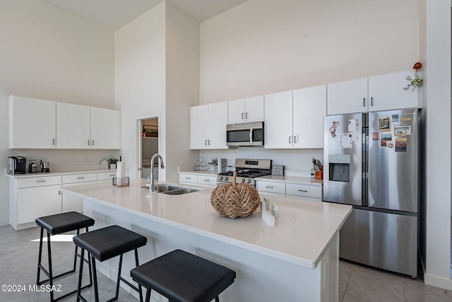 kitchen with white cabinetry, sink, stainless steel appliances, and a kitchen bar