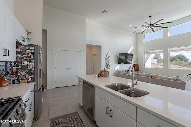 kitchen featuring a towering ceiling, appliances with stainless steel finishes, open floor plan, and a sink