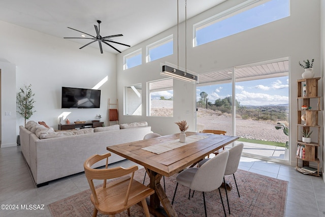 dining area featuring a high ceiling, light tile patterned flooring, and ceiling fan