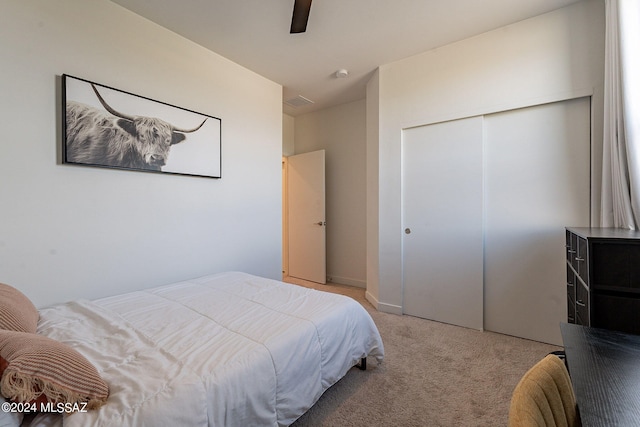 bedroom featuring a ceiling fan, a closet, and light colored carpet