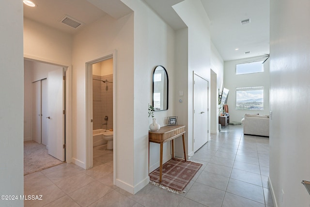 corridor featuring light tile patterned floors and a high ceiling