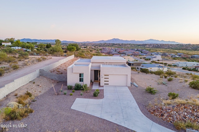 view of front of home with driveway, fence, a mountain view, and stucco siding