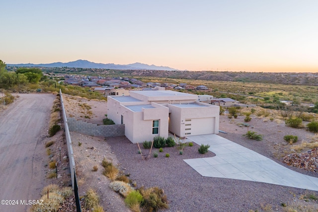 adobe home featuring a garage, concrete driveway, fence, a mountain view, and stucco siding