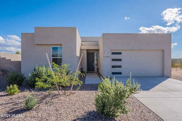 view of front of property featuring a garage, concrete driveway, and stucco siding