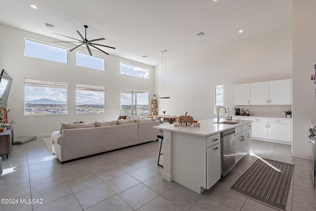 kitchen with sink, light tile patterned floors, dishwasher, white cabinets, and a center island with sink