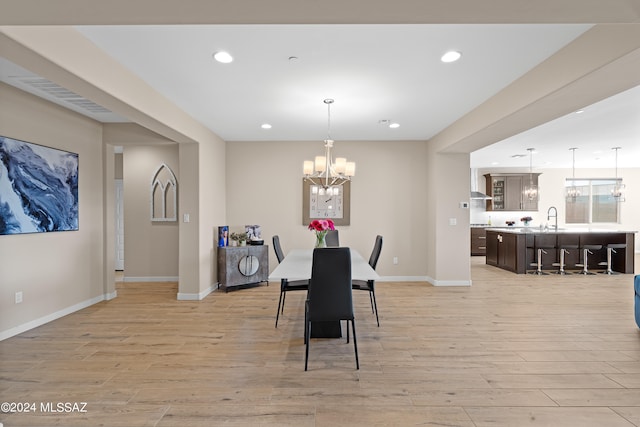 dining room featuring light hardwood / wood-style flooring, sink, and a notable chandelier