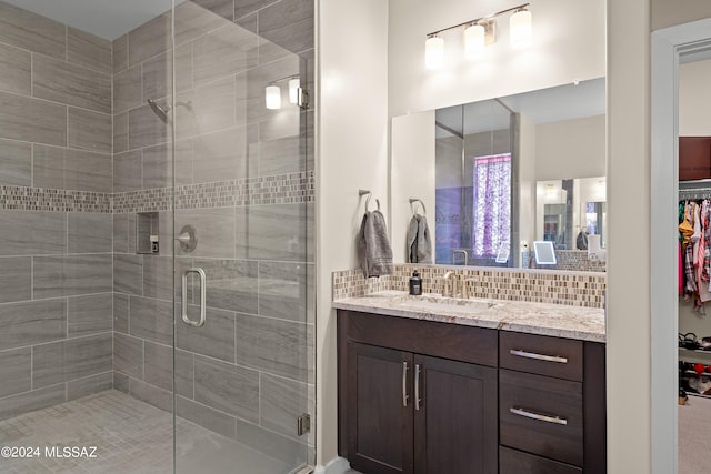 bathroom featuring a shower with door, decorative backsplash, and vanity