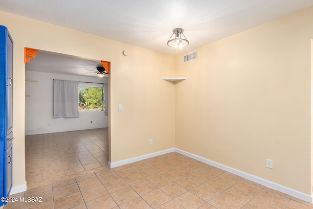 tiled empty room with ceiling fan with notable chandelier