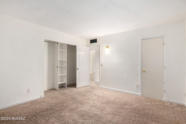 unfurnished bedroom featuring light carpet and a closet