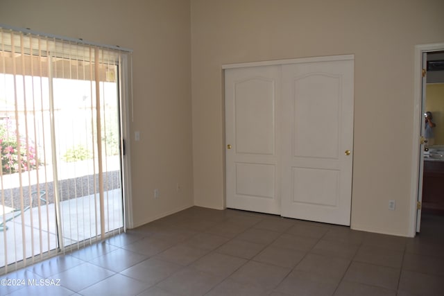 unfurnished bedroom with tile patterned floors, a closet, and access to outside