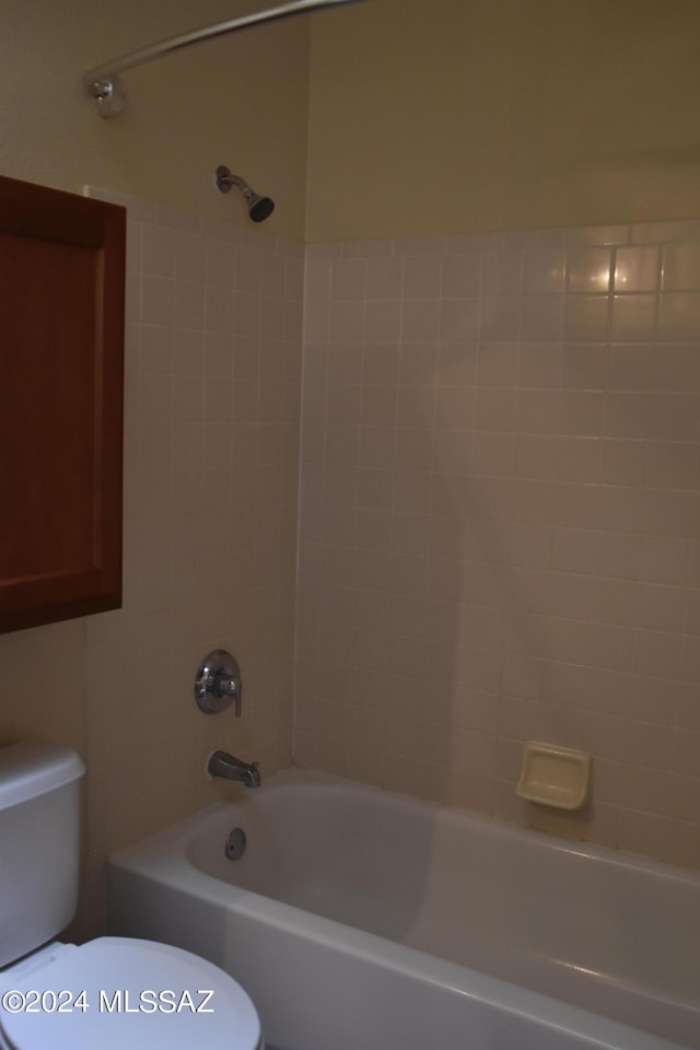 bathroom with tiled shower / bath combo and toilet