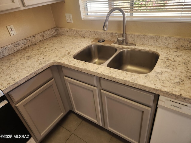 details with dishwasher, light stone countertops, and sink