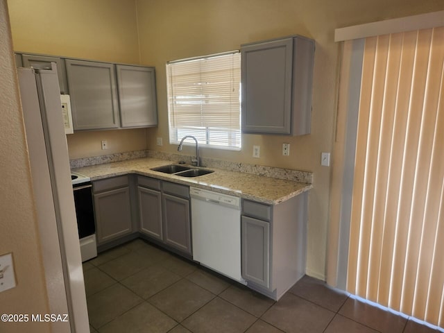 kitchen featuring tile patterned floors, sink, gray cabinetry, white appliances, and light stone countertops