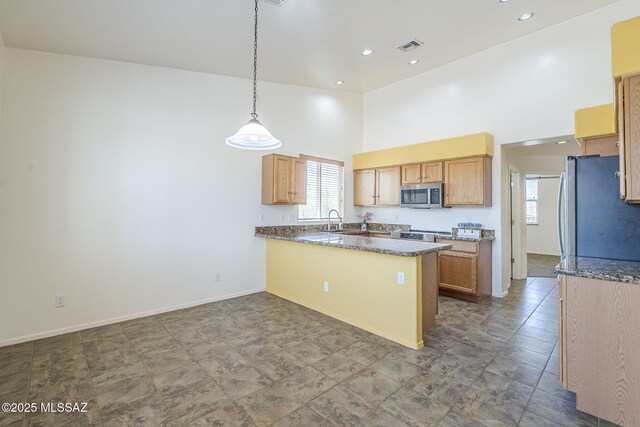 1888 Circulo Guatemala, Rio Rico, AZ 85648 - kitchen with stainless steel appliances, a high ceiling, a peninsula, a sink, and hanging light fixtures