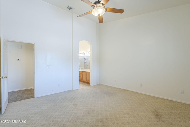1888 Circulo Guatemala, Rio Rico, AZ 85648 - unfurnished bedroom featuring arched walkways, light carpet, connected bathroom, baseboards, and a ceiling fan