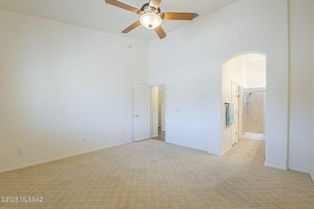 1888 Circulo Guatemala, Rio Rico, AZ 85648 - spare room featuring arched walkways, light colored carpet, ceiling fan, high vaulted ceiling, and baseboards