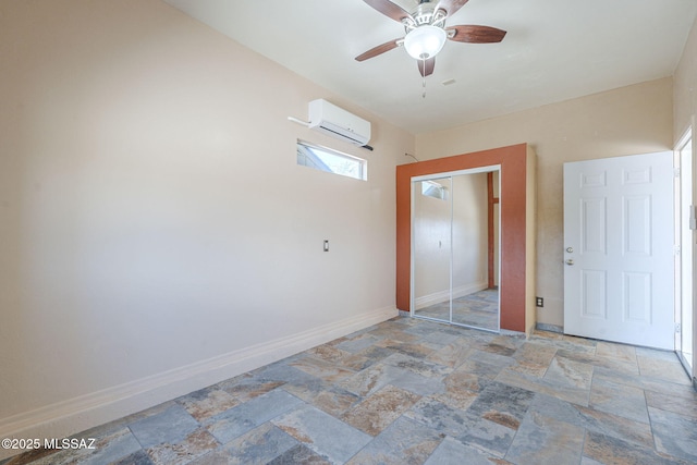 1888 Circulo Guatemala, Rio Rico, AZ 85648 - unfurnished bedroom featuring stone tile floors, a wall unit AC, baseboards, a closet, and a ceiling fan