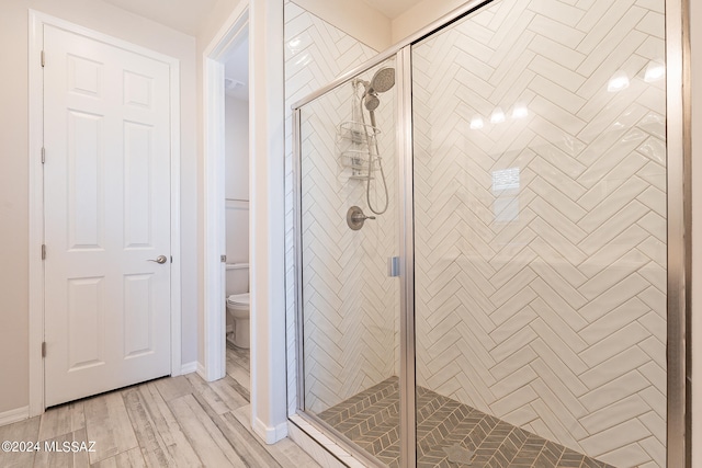 bathroom featuring toilet, hardwood / wood-style flooring, and a shower with shower door