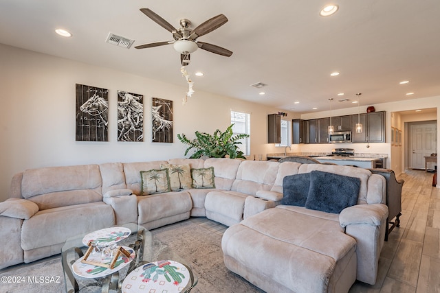 living room with light hardwood / wood-style flooring and ceiling fan