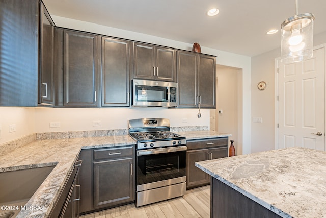 kitchen with dark brown cabinets, stainless steel appliances, and light hardwood / wood-style floors