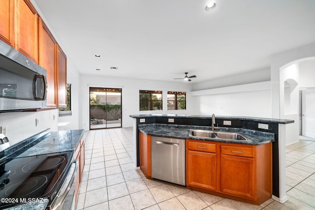 kitchen with light tile patterned floors, ceiling fan, dark stone counters, sink, and stainless steel appliances