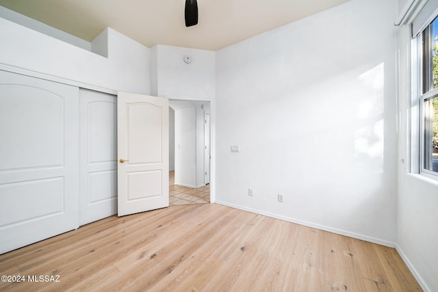 unfurnished bedroom with a closet, ceiling fan, and light wood-type flooring