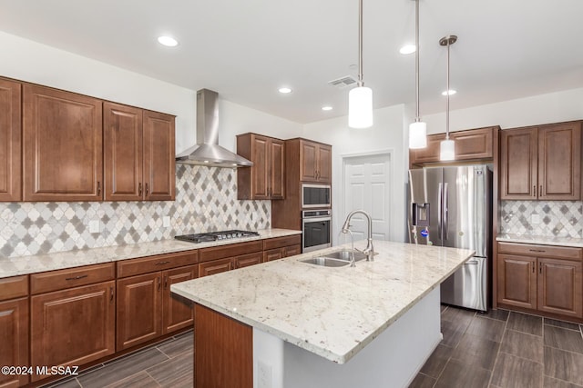 kitchen featuring a kitchen island with sink, sink, wall chimney exhaust hood, and appliances with stainless steel finishes