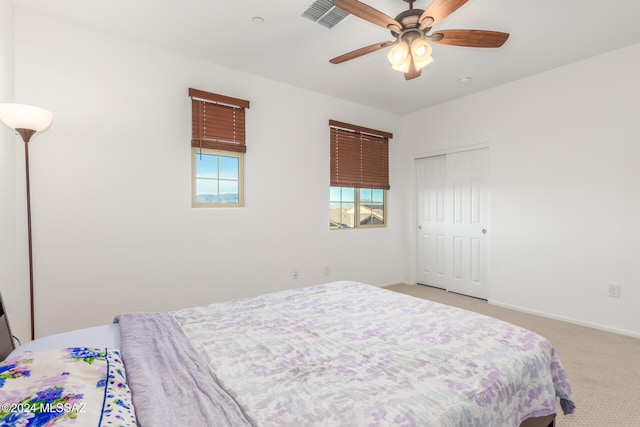 bedroom with a closet, light colored carpet, and ceiling fan