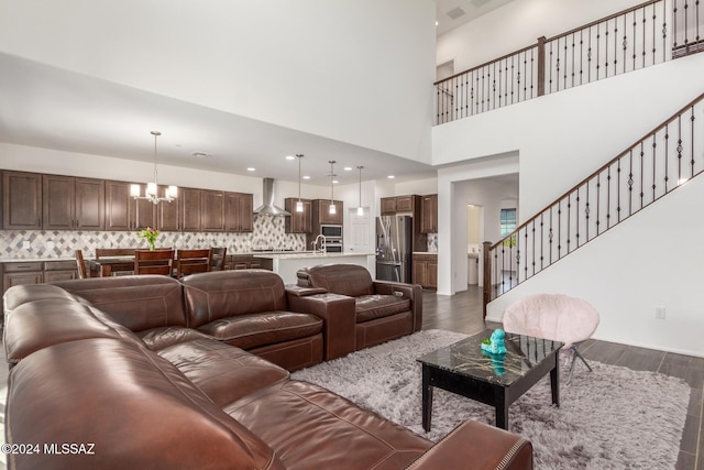 living room with a notable chandelier, sink, a towering ceiling, and dark wood-type flooring