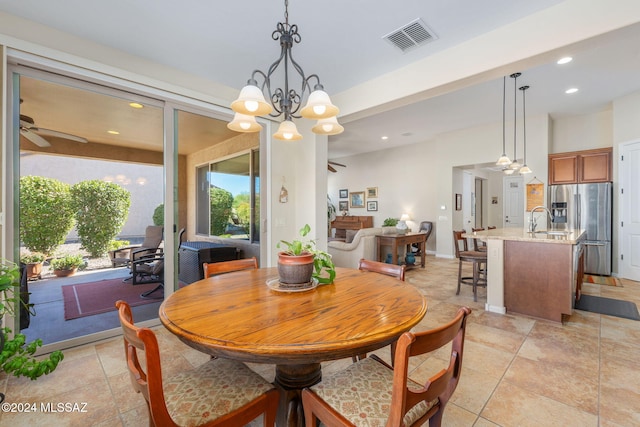 dining room with ceiling fan with notable chandelier and sink