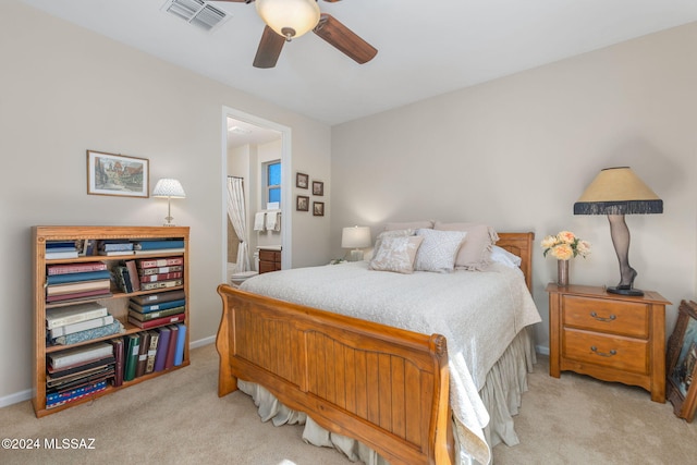 bedroom featuring ceiling fan, light carpet, and ensuite bath