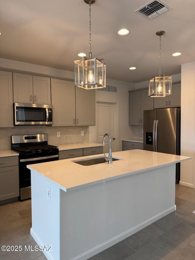 kitchen featuring light countertops, gray cabinetry, visible vents, appliances with stainless steel finishes, and a sink