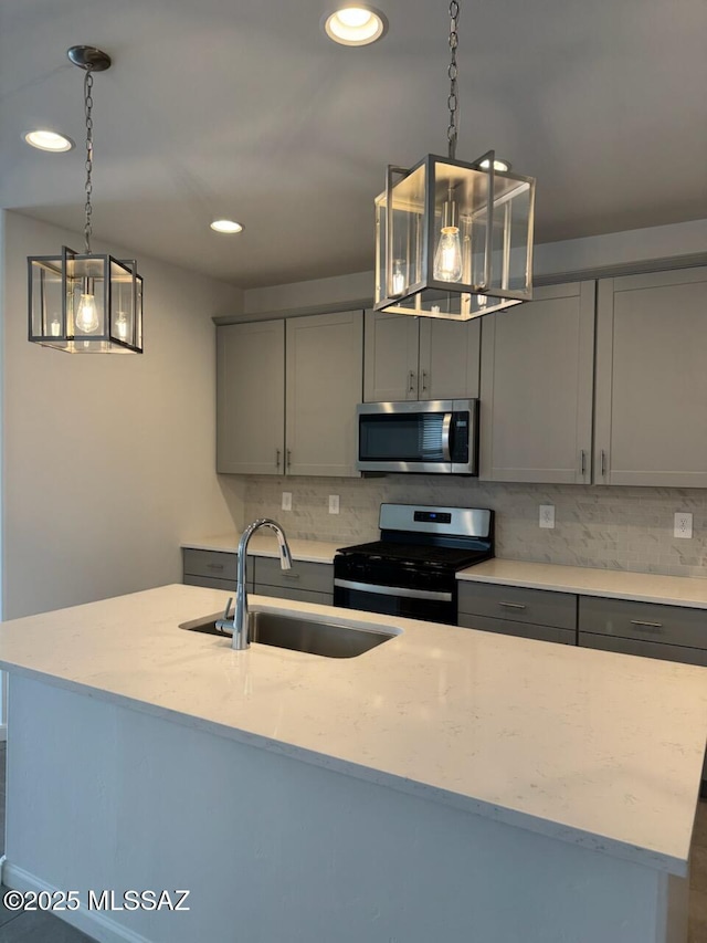 kitchen with a sink, gray cabinets, tasteful backsplash, and appliances with stainless steel finishes