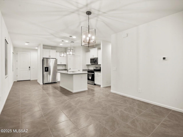 kitchen featuring a sink, a chandelier, stainless steel appliances, light tile patterned flooring, and an island with sink