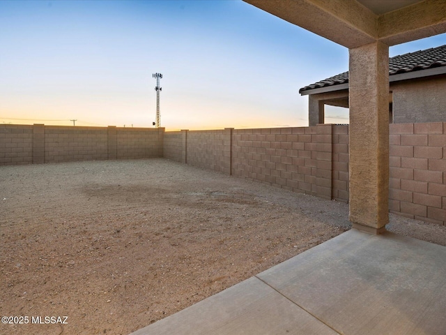 yard at dusk featuring a patio and a fenced backyard